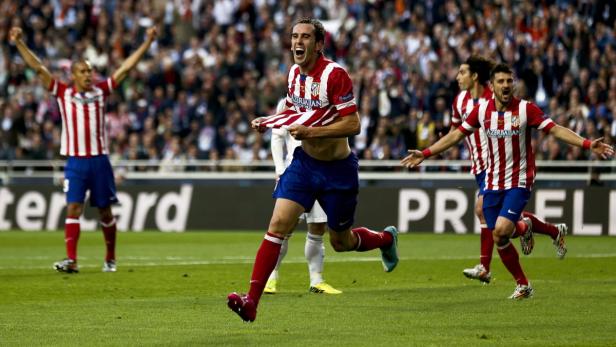 Ein Fußballspieler von Atlético Madrid jubelt mit seinem Trikot in der Hand.