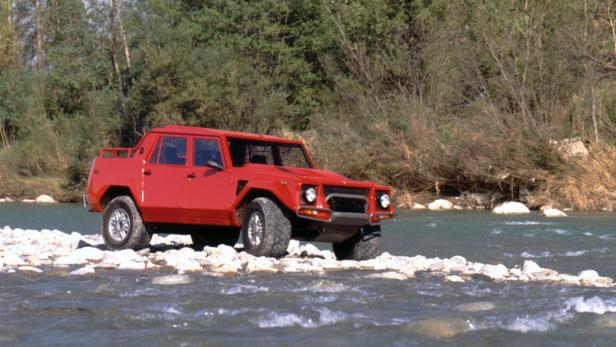 Ein roter Lamborghini LM002 fährt durch einen Fluss.