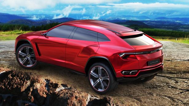 Ein roter Lamborghini Urus steht auf einem unebenen Untergrund vor einer Berglandschaft.