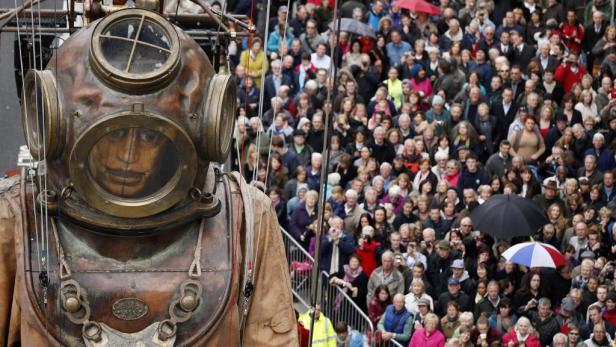 Eine riesige, mechanische Taucherfigur steht vor einer Menschenmenge.