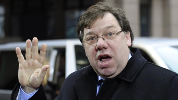 Ein Mann mit Brille und dunklem Mantel winkt mit der Hand.