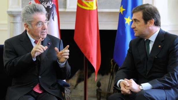 Zwei Männer in Anzügen unterhalten sich vor Flaggen von Österreich, Portugal und der EU.