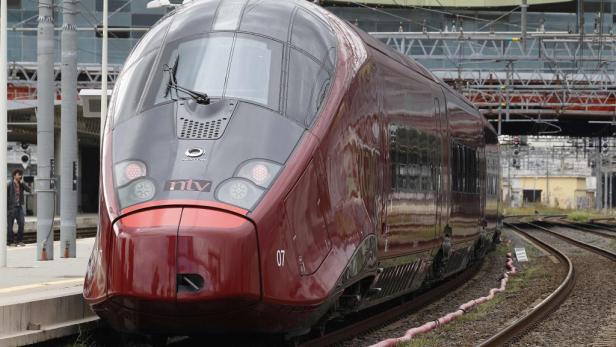 Ein roter Hochgeschwindigkeitszug der NTV steht auf einem Bahnhofsgleis.