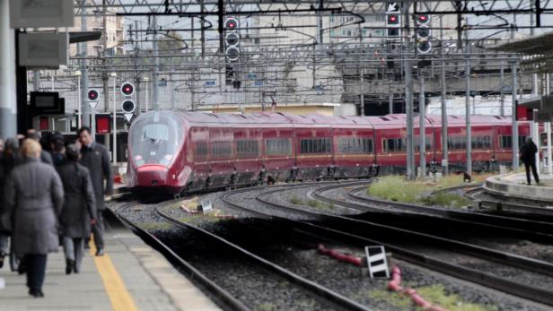 Ein roter Hochgeschwindigkeitszug fährt in einen Bahnhof ein.