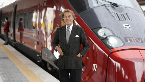 Ein Mann in einem Anzug posiert vor einem roten Hochgeschwindigkeitszug von Alstom NTV.