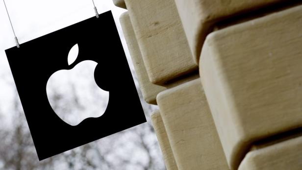 Das Apple-Logo hängt an einer Schnur vor einer Steinmauer.
