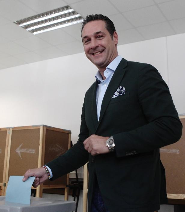 Ein lächelnder Mann wirft einen blauen Stimmzettel in eine Wahlurne.