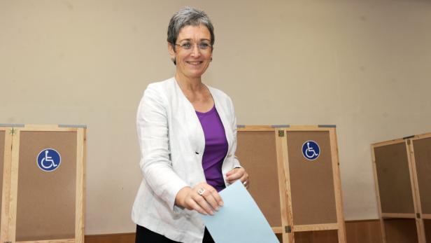 Eine Frau wirft einen blauen Wahlzettel in eine Wahlurne.