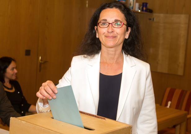 Eine Frau wirft einen Stimmzettel in eine Wahlurne.