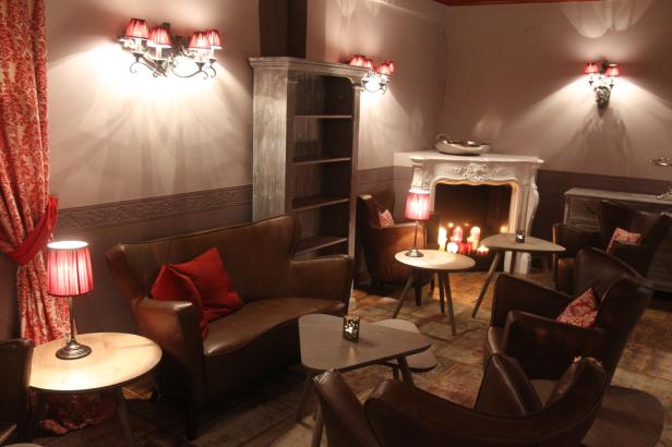 Ein gemütlicher Aufenthaltsraum mit braunen Ledersesseln und einem Kamin.