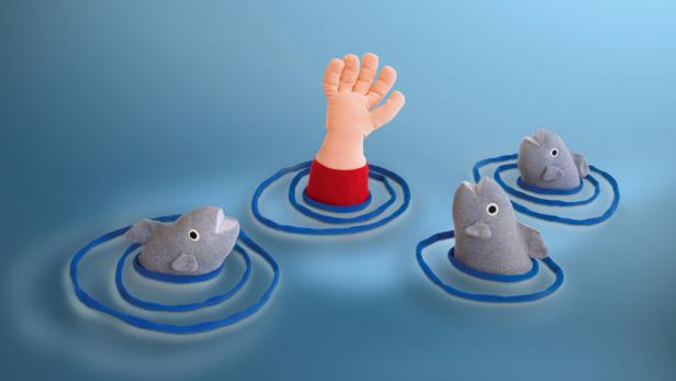 Eine Stoffhand ragt aus einem blauen Meer, umgeben von drei Stofffischen.