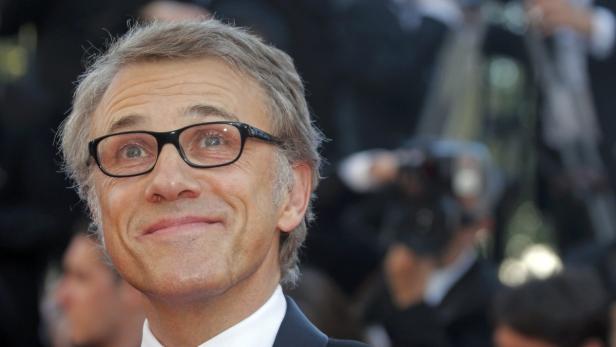 Christoph Waltz lächelt mit Brille vor einer Menschenmenge.