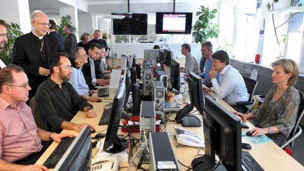 Mehrere Personen arbeiten an Computern in einem hellen Büro.