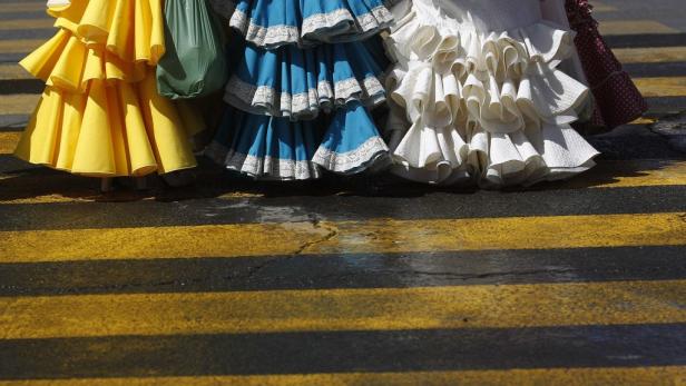 Mehrere Personen in farbenfrohen Flamenco-Kleidern stehen auf einem Zebrastreifen.