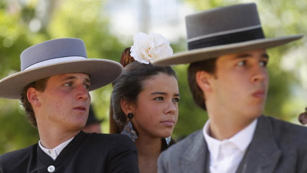 Eine Gruppe junger Leute in traditioneller andalusischer Kleidung mit Hüten und Blumen im Haar.