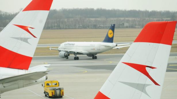 Eine Lufthansa-Maschine rollt am Flughafen, im Vordergrund die Leitwerke von Austrian Airlines Flugzeugen.