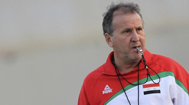 Ein Mann mit einer Pfeife um den Hals trägt ein Sporttrikot mit der irakischen Flagge.