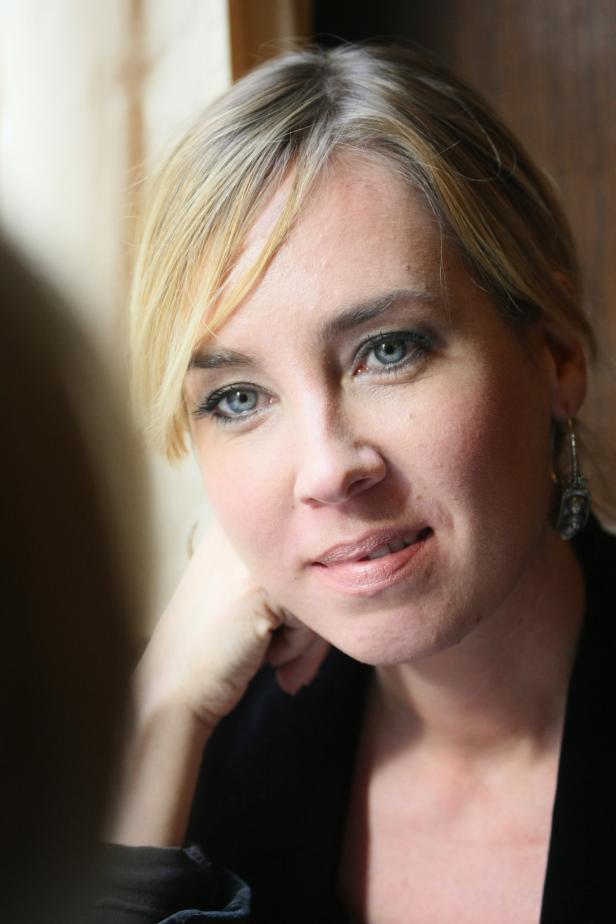 Eine Frau mit blonden Haaren und blauen Augen blickt in die Kamera.