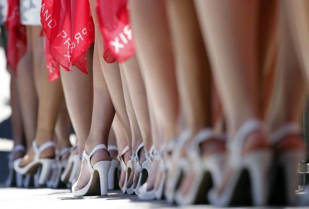 Eine Reihe von Frauenbeinen in weißen High Heels mit roten Tüchern.