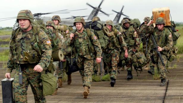 Eine Gruppe von US-Soldaten geht mit Ausrüstung an Hubschraubern vorbei.