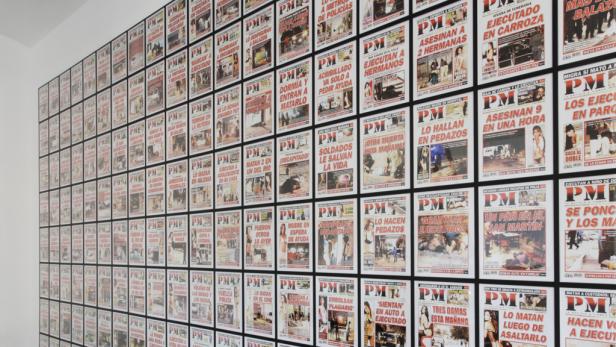 Eine Wand bedeckt mit vielen Zeitungsartikeln über Gewaltverbrechen.