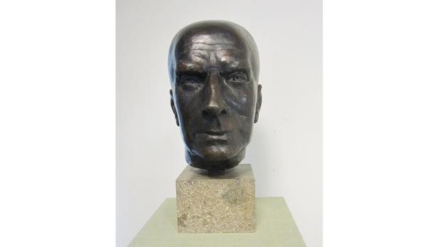 Eine Bronzebüste eines Mannes auf einem Steinsockel.