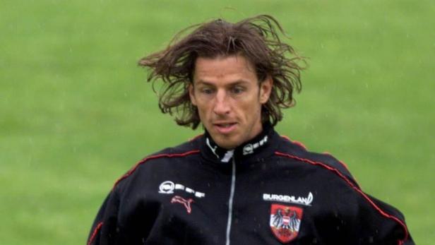 Ein Mann mit langen Haaren trägt eine Trainingsjacke des Burgenlandes.