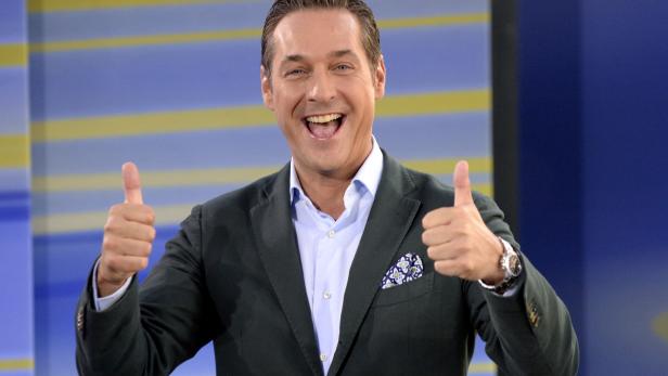 Ein lächelnder Mann im Anzug zeigt mit beiden Daumen nach oben.