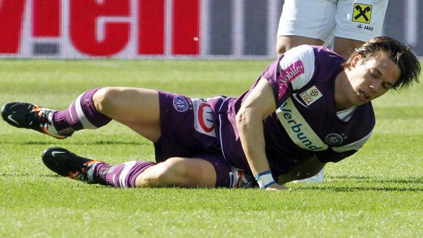 Ein Fußballspieler liegt verletzt auf dem Rasen.