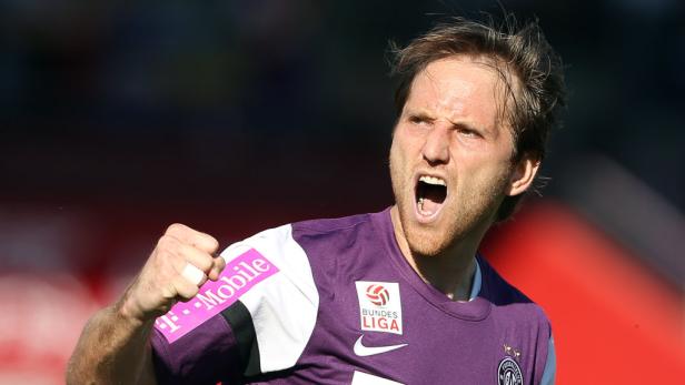 Ein Fußballspieler in lila Trikot jubelt mit geballter Faust.