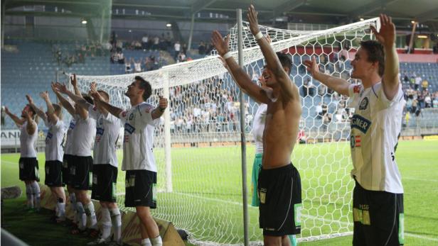 Eine Fußballmannschaft jubelt mit erhobenen Armen vor einem Tornetz.