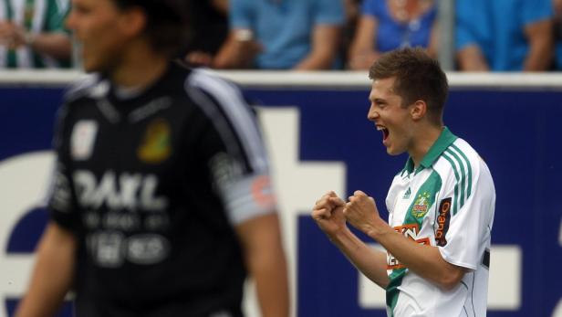 Ein jubelnder Fußballspieler im weiß-grünen Trikot.