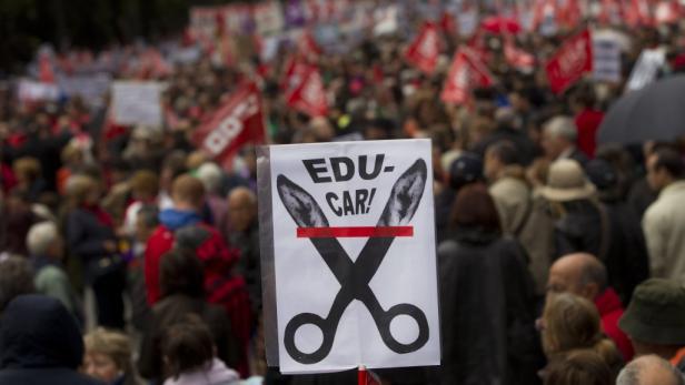 Eine Demonstration gegen Kürzungen im Bildungsbereich mit einem Plakat mit einer Schere.