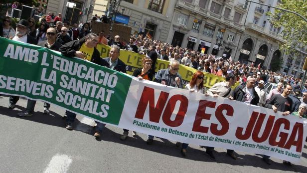 Menschen demonstrieren mit einem Banner für Bildung und soziale Dienste in Valencia.