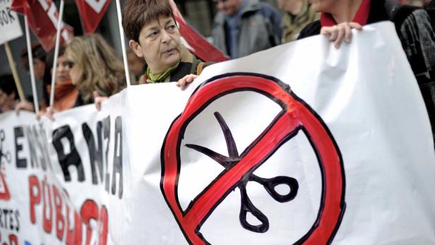 Demonstranten halten ein Transparent mit einem durchgestrichenen Scherensymbol hoch.