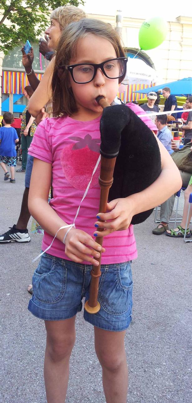 Ein junges Mädchen mit Brille spielt auf einem Dudelsack.