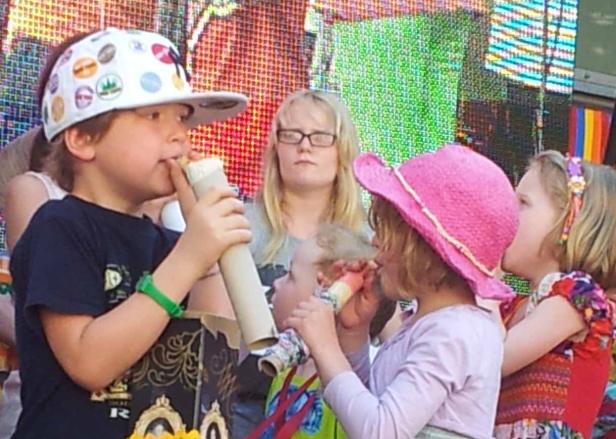 Eine Gruppe Kinder bläst auf einer Veranstaltung in Papierhörner.