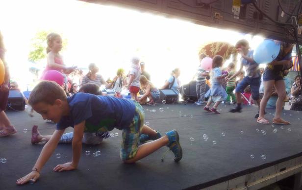 Kinder spielen mit Seifenblasen auf einer Bühne.