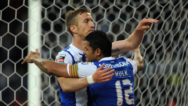 Zwei Fußballspieler umarmen sich vor einem Tornetz.