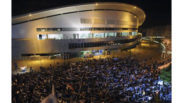 Eine große Menschenmenge versammelt sich nachts vor einem Stadion.