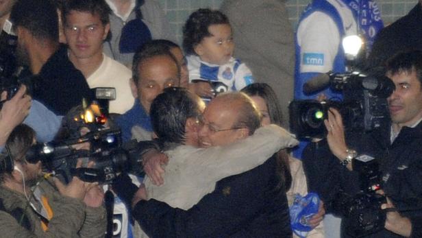 Zwei Männer umarmen sich inmitten einer Menschenmenge und Kameras.