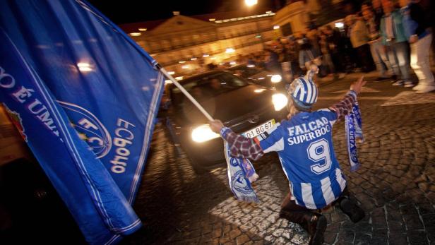 Ein Fußballfan von FC Porto jubelt auf der Straße mit einer Fahne.