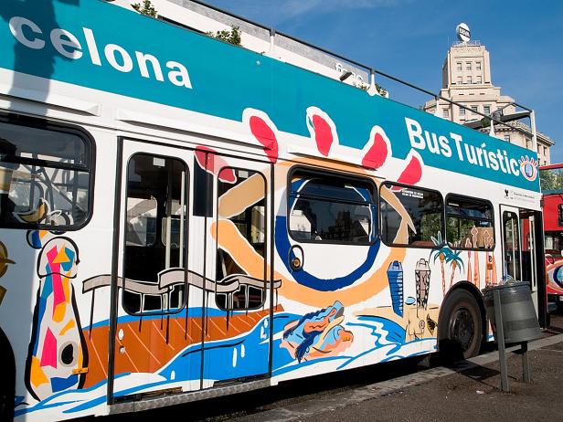 Ein Bus Turístic in Barcelona mit bunten Illustrationen an der Seite.