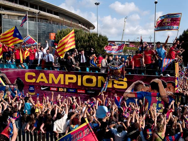 Fans feiern den FC Barcelona auf einem offenen Bus mit Fahnen und Transparenten.