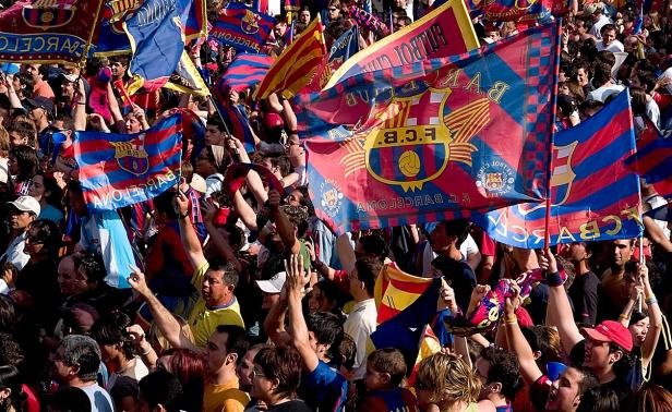 Eine Menschenmenge schwenkt Fahnen des FC Barcelona.