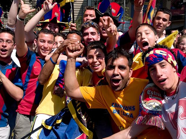 Eine Gruppe jubelnder Fußballfans, viele in den Farben des FC Barcelona gekleidet.