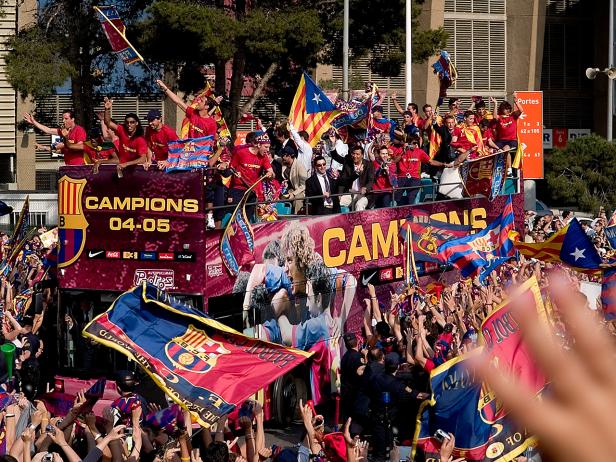 Fans feiern den FC Barcelona auf einem offenen Bus mit katalanischen Flaggen.