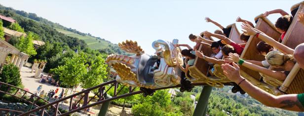 Menschen fahren mit einer Achterbahn im Themenpark bei strahlendem Sonnenschein.