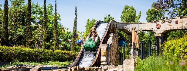 Eine Frau fährt mit einer Wasserbahn durch eine üppige Parklandschaft.