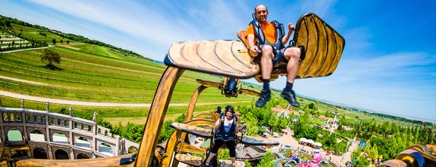 Zwei Personen fahren mit einem Fahrgeschäft in einem Freizeitpark.